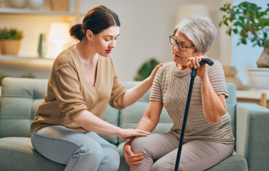 Elderly patient and caregiver spending time together. Senior woman holding cane.